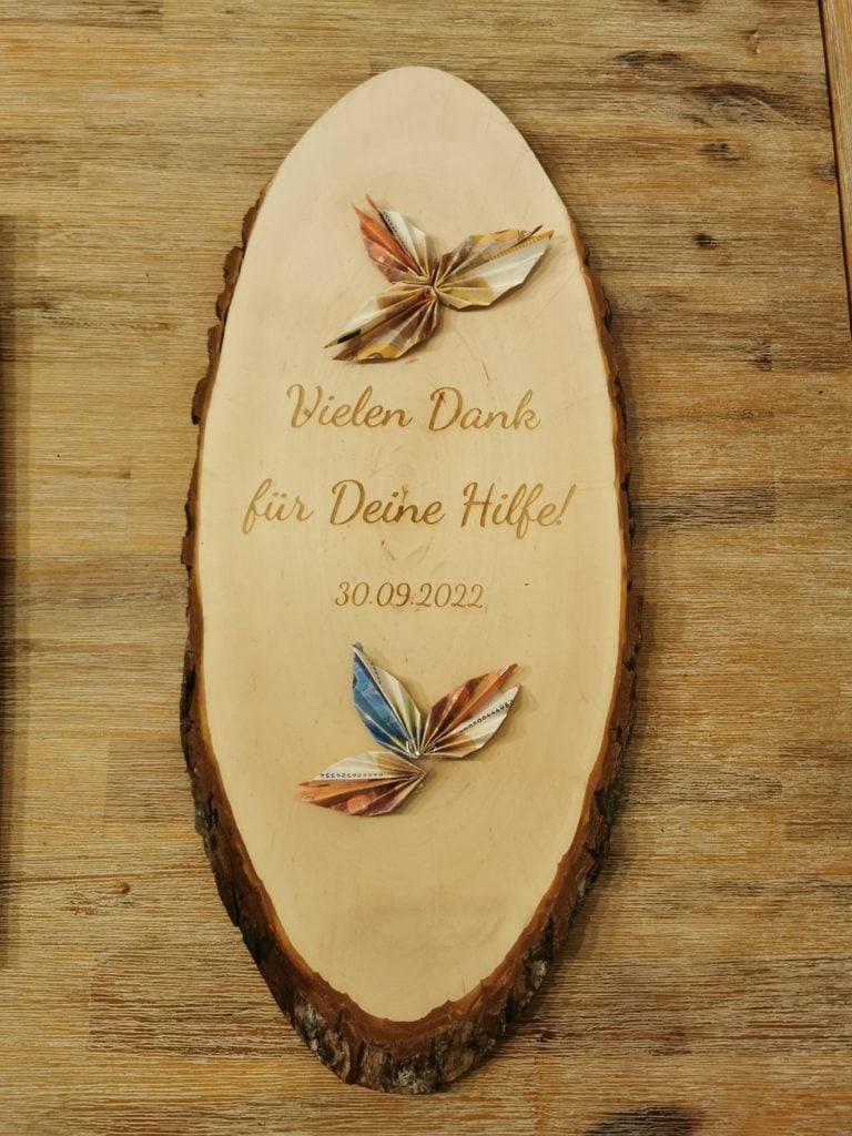 Kunstvoller Holzschild mit gefalteten Geldscheiben-Schmetterlingen und persönlicher Dankesbotschaft, ideal für individuelle Geschenke und Dekorationen bei Laserart Kevin Langer in Lübbecke.
