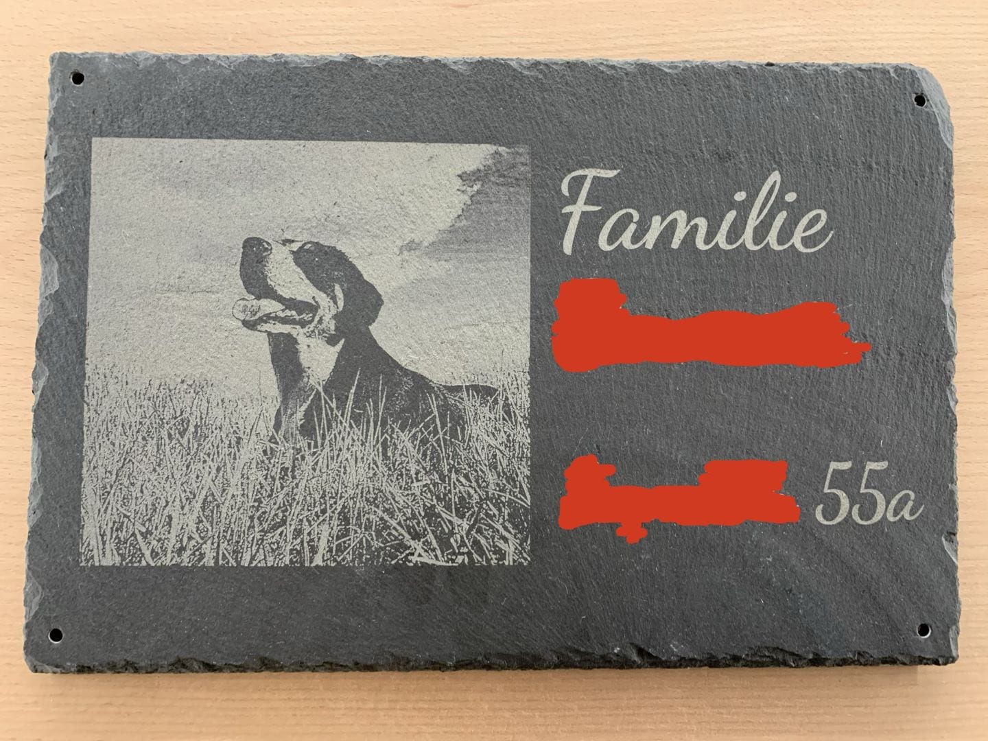Hundporträt auf einer Schieferplatte mit lasergraviertem Bild und personalisierter Beschriftung als Türschild.